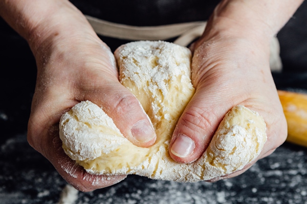 hands of cook beating up pastry for cookies vertical studio shot - Орешки со сгущёнкой