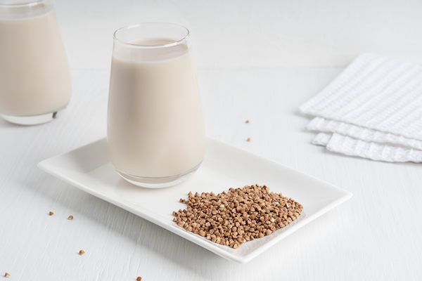 lactose free vegetarian buckwheat milk served in glass on plate with seeds and textile on table - Кулинарные секреты для одиноких