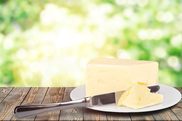 pat of fresh farm butter on a butter dish with a knife on backgrouund - Кулинарные секреты для одиноких