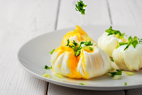 poached eggs decorated with fresh herbs on a white plate - Секреты приготовления яиц всмятку, "в мешочек" и вкрутую. Пошаговая инструкция