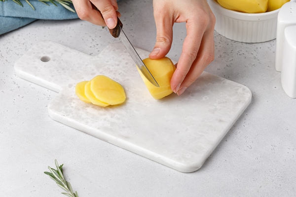 step by step recipe of potato gratin hands cut potatoes on marble board potato casserole - Картофель, запечённый с лососем