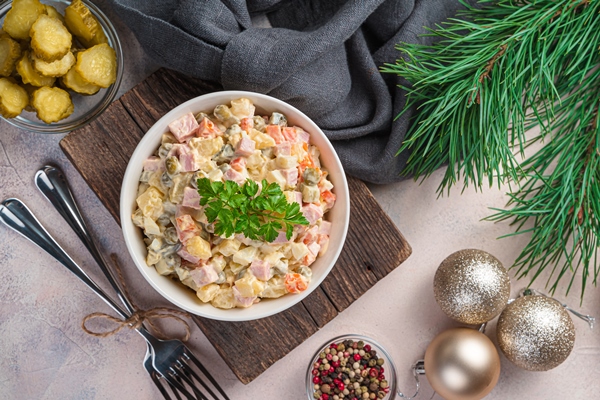 traditional olivier salad of finely chopped vegetables and sausage on the background of christmas decorations top view horizontal - Рекомендации по расчёту банкетных блюд и напитков