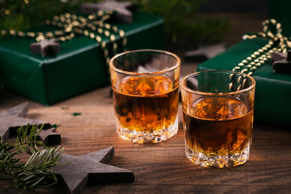 two shot glasses of whiskey or bourbon with holiday decoration on wooden background new year christmas and winter holidays whiskey mood concept - Рекомендации по расчёту банкетных блюд и напитков