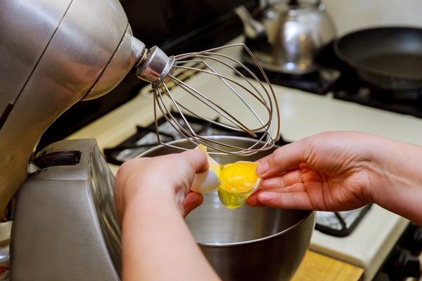 woman separates egg whites from yolk in mixer bowl 1 - Драчена