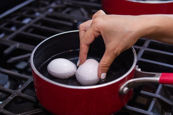 young girl prepares beautiful eggs in skillet for breakfast - Секреты приготовления яиц всмятку, "в мешочек" и вкрутую. Пошаговая инструкция