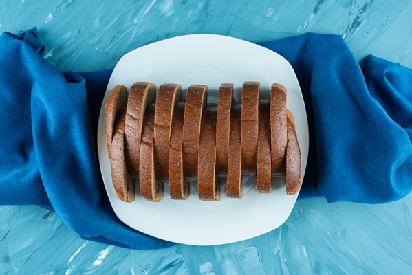a white plate of sliced brown fresh bread on a blue background - Рижский хлеб