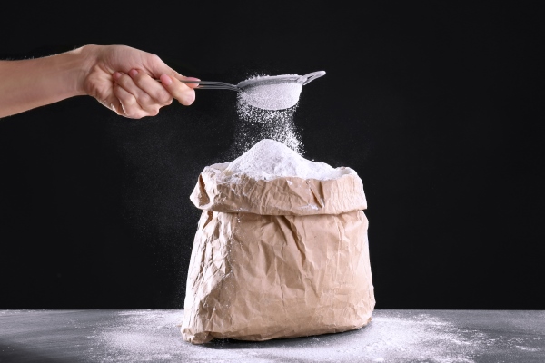 bag of flour and female hand with sieve on dark background - Рижский хлеб