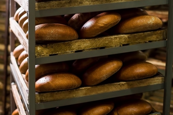 baker puts freshly baked bread on the shelves selling bread bakery plant produces social bread baking yeast breads harvesting - Ржаной обдирной хлеб