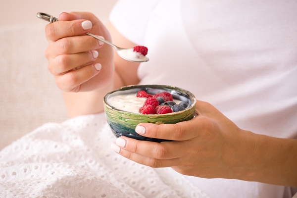 closeup of a young woman holding a green bowl with organic yogurt and fresh berries - Средиземноморская диета