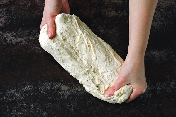 yeast dough in female hands on a dark background - Рогалики по ГОСТу