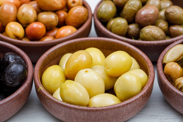 assorted olives in a clay bowls on white wood plank side view - Оливки и маслины: в чём разница