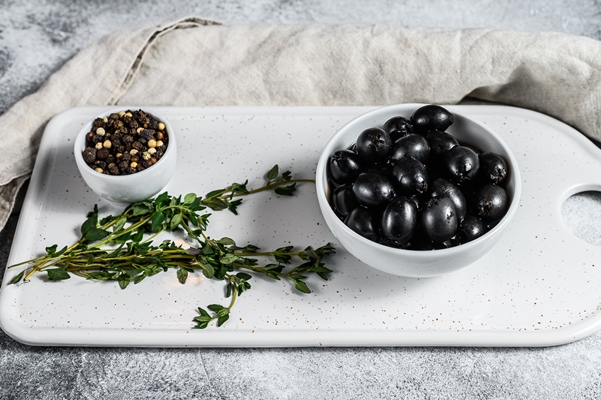 black olives on a white chopping board - Польза и вред оливок