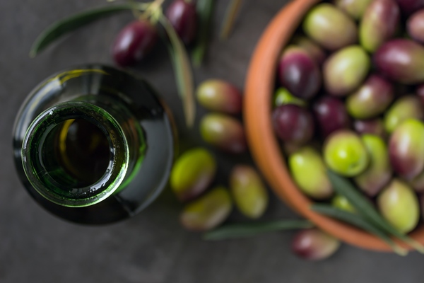 bottle of green glass with olive oil next to ripe olives - Оливковое масло