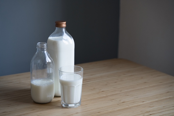 bottles of milk and glass on light colored wooden table - Углеводная питательность рациона