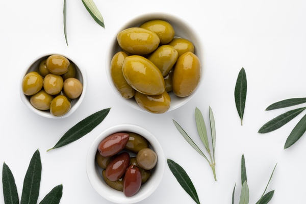bowl with green olives and olive leaves on white background - Салат "Оливье" (старинный рецепт)