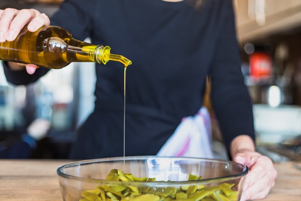 crop hands of woman cooking salad in kitchen - Польза и вред оливок