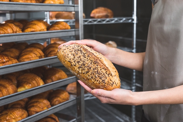 female baker s hand holding fresh loaf of bread - Углеводная питательность рациона