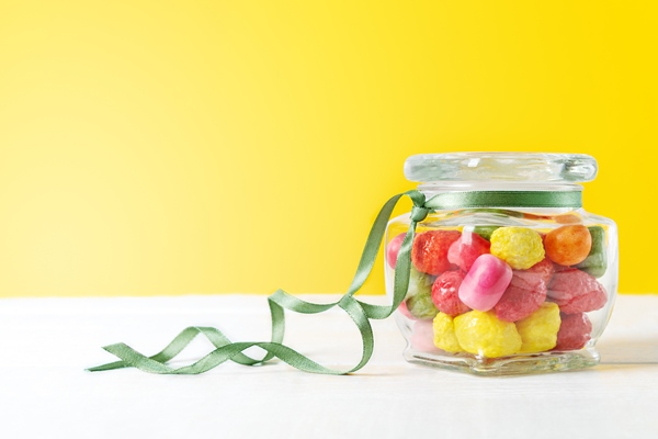 glassware with different chewy multi colored candies in the form of fruits with a yellow backdrop banner - Углеводная питательность рациона