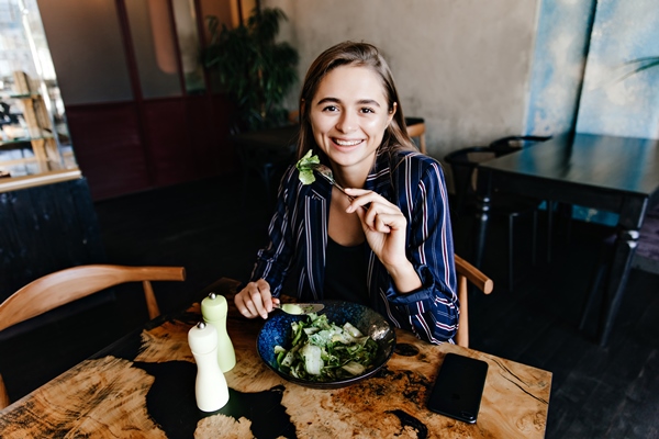 good humoured caucasian woman enjoying healthy food indoor shot of smiling girl eating salad - Углеводная питательность рациона