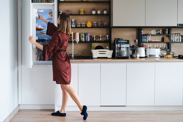 hungry woman looking for food in the fridge at home but dont have much there white kitchen furniture home wear red silk robe - Оливковое масло