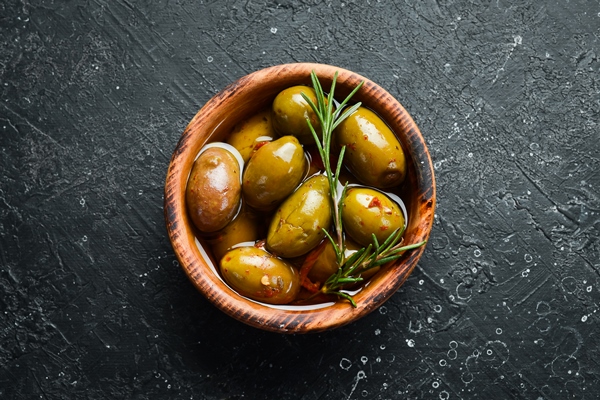 marinated olives in a wooden bowl on a stone background free space for - Использование оливок в кулинарии