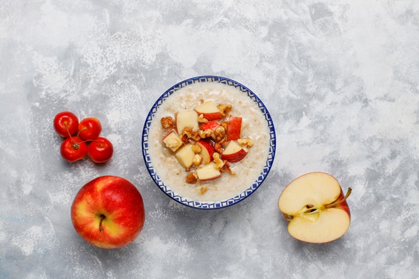 oatmeal porridge in a bowl with honey and red apple slices top view - Углеводная питательность рациона