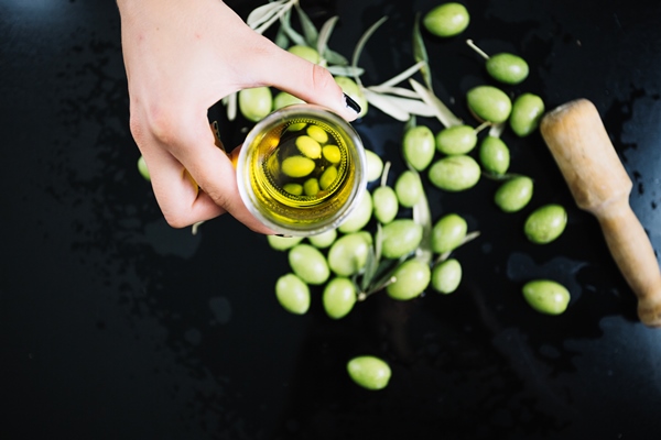 person holding olive oil over olives - Оливки и маслины: в чём разница