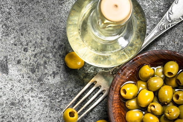 pickled olives with olive oil on a rustic table - Оливковое масло