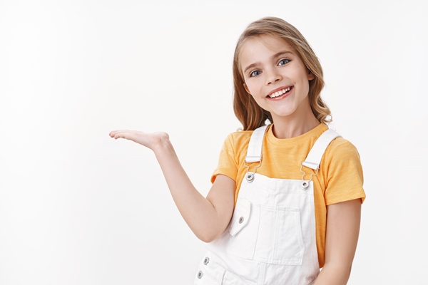 pretty clever little girl child with blond hairstyle in yellow t shirt and overalls hold something on palm introduce product blank white copy space smiling joyful brag what she got b day present - Бородинский хлеб: история и современность