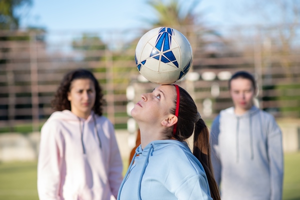 side view of teenage girl playing with ball sporty girl in sportswear holding ball on forehead practicing playing and showing skills of training for her team healthy lifestyle team sport concept - Углеводная питательность рациона