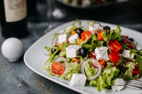 sliced vegetables greece salad with cheese olive oils along with red wine on grey - Использование оливок в кулинарии