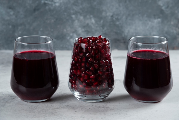three glass cups of pomegranate juice on marble - Продукты против вирусов