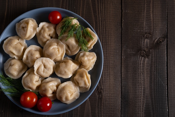 blue plate with boiled homemade dumplings with dill and tomatoes - Пельмени с рыбной начинкой