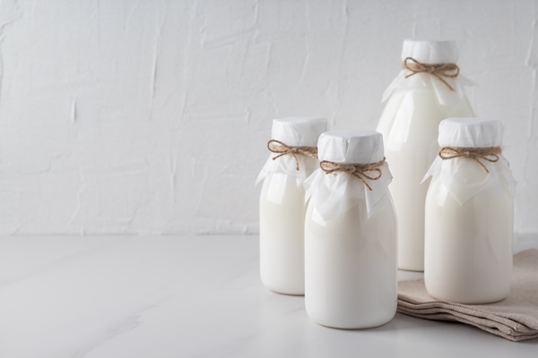 bottles of organic kefir yogurt or ayran on marble table copy space fermented dairy milk product - Блинцы заварные на кефире