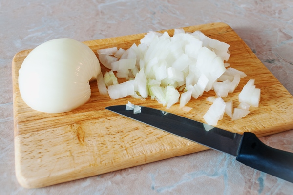 chopped onions on a wooden board - Пельмени