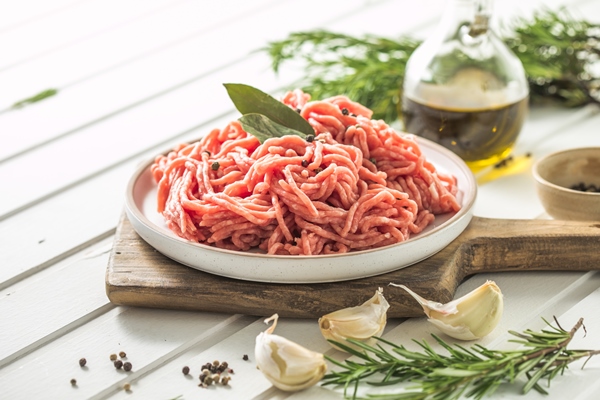 fresh raw beef minced meat with herbs and rosemary on wooden board on a light background banner menu recipe place for text top view - Домашние пельмени из заварного теста