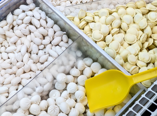 frozen dumplings sold by weight in a refrigerator container on a store counter - Пельмени