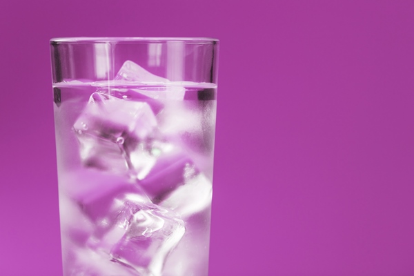 glass with water and ice cubes on a pink background - Русские пельмени