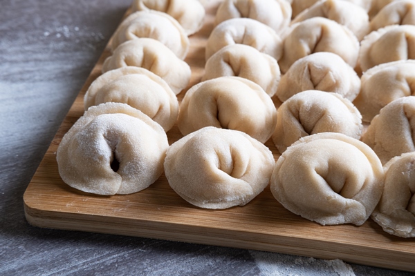 homemade dumplings of meat and dough closeup on a wooden board - Пельмени