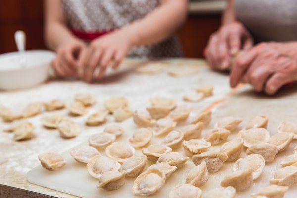 little girl with grandmother in the kitchen sculpts dumplings - Пельмени