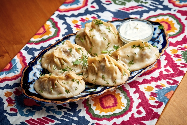 manti a type of dumplings stuffed with meat and served on a plate - Пельмени