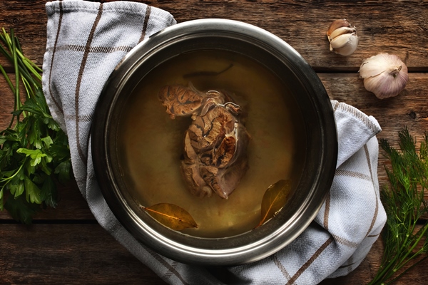 meat broth from beef in a metal pan on the wooden table - Пельмени