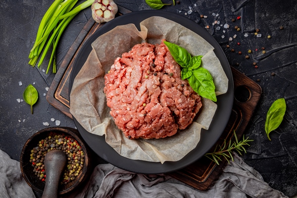 minced meat in a plate and spices on a black background top view high quality photo - Уральские пельмени