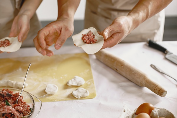 people while preparing dumplings asian people in aprons - Пельмени