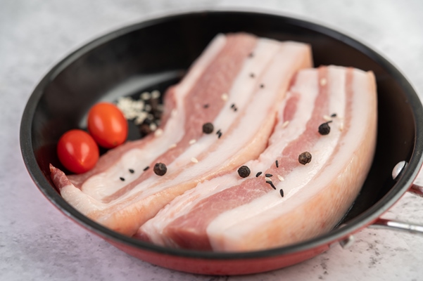 pork belly in a pan with pepper seeds tomatoes and spices - Пельмени