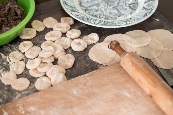 preparation of dumplings meat filling in a cup dough dumplings and a board with a rolling pin - Русские пельмени