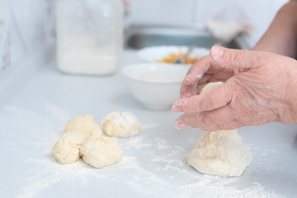 senior woman hands form blanks for pies on a white kitchen table with blurred grated apple and sugar - Уральские пельмени