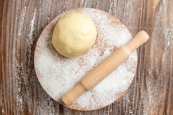 top view raw dough piece with flour on a wooden desk meal flour bake dough - Пельмени с рыбной начинкой