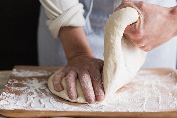 a female baker kneading the dough with flour on chopping board - Галета со шпинатом, постная