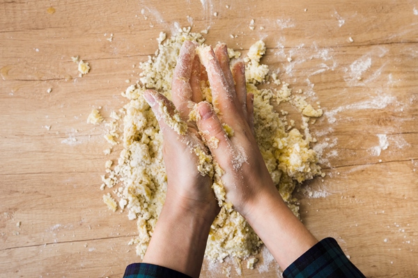close up of a woman s hand kneading the dough for preparing italian gnocchi on wooden desk - Галета с ревенем